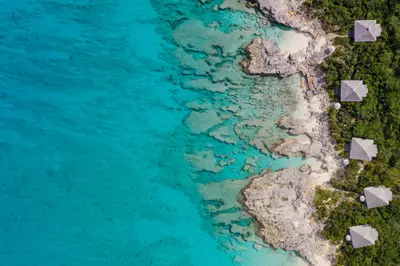 Aerial view of Amanyara's Ocean Cove and Ocean Pavilions beside the rocky turquoise shoreline